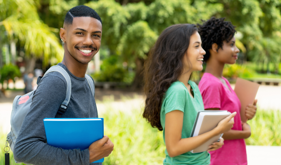 jovem negro estudante do ensino médio andando por um campo acompanhado de duas meninas